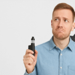 A man with a vape in his hand, having a puzzled expression, with an airplane graphic behind him