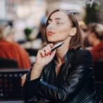 Young adult woman vaping outdoors, highlighting legal age concerns