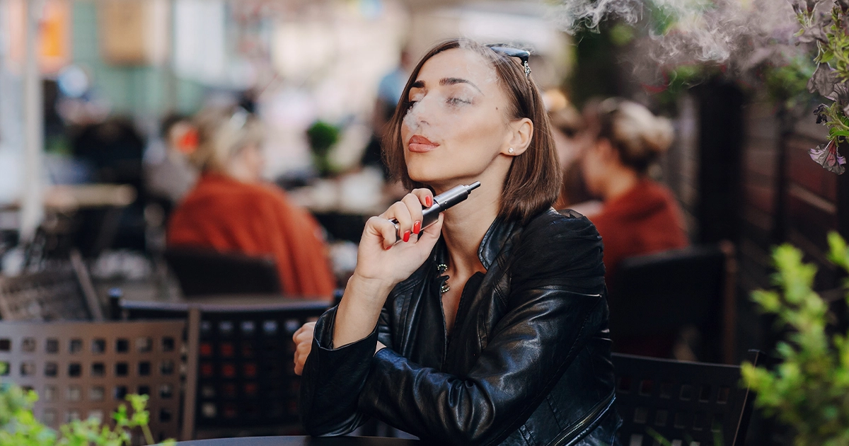Young adult woman vaping outdoors, highlighting legal age concerns