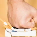 Hand crushing a pack of cigarettes, symbolizing quitting smoking.
