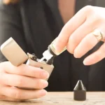 Person refilling a vaping device with liquid vape juice.