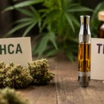 Cannabis flowers beside vape cartridge and text signs on wood